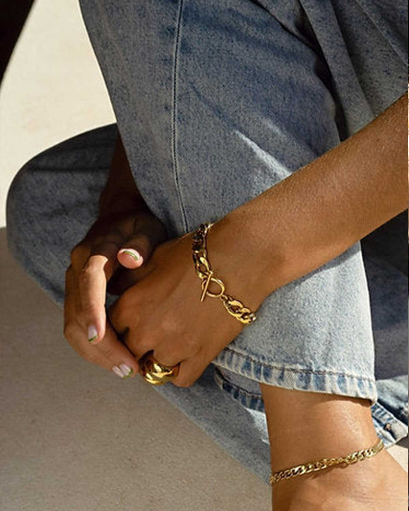 jeans styled with gold anklet, bracelet, and rings 