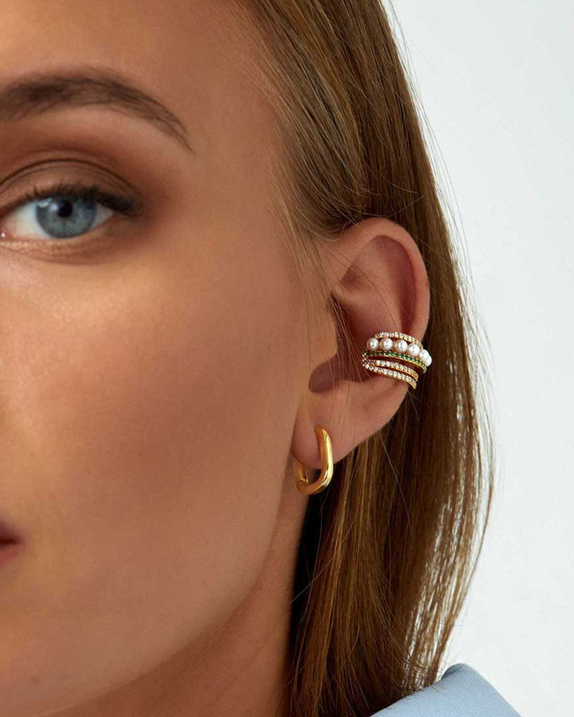 half face of model wearing small paper clip gold hoops and pearl and crystal ear cuff 