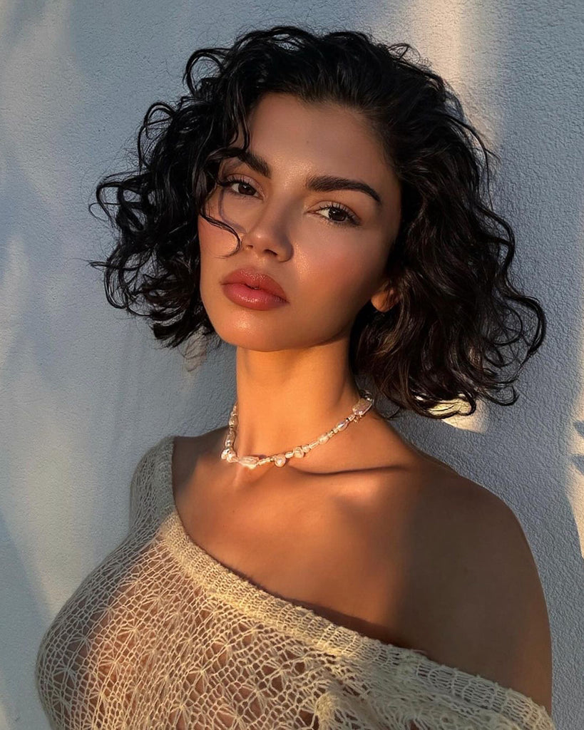 model with short dark hair wearing pearl necklace in the sunset