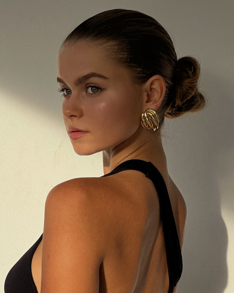 gold statement earrings on a model with black dress