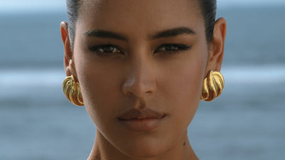 chunky gold earrings on a dark-skinned model