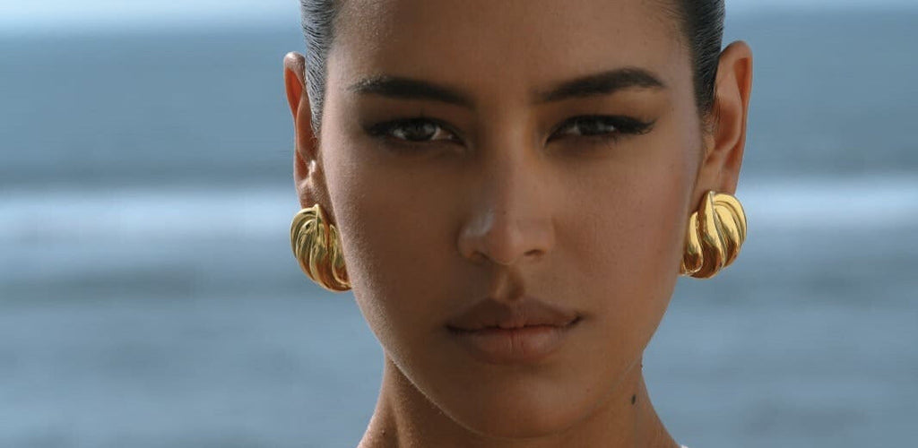 close up on gold statement earrings on a model 