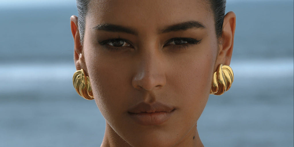 gold statement earrings on a model