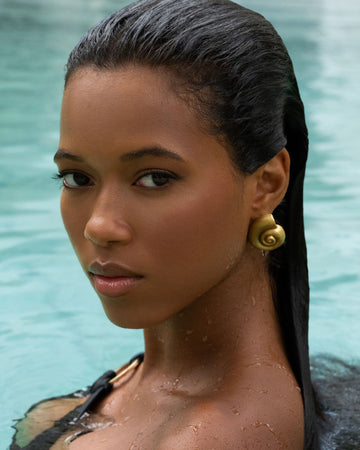 gold shell earrings on a model with dark skin