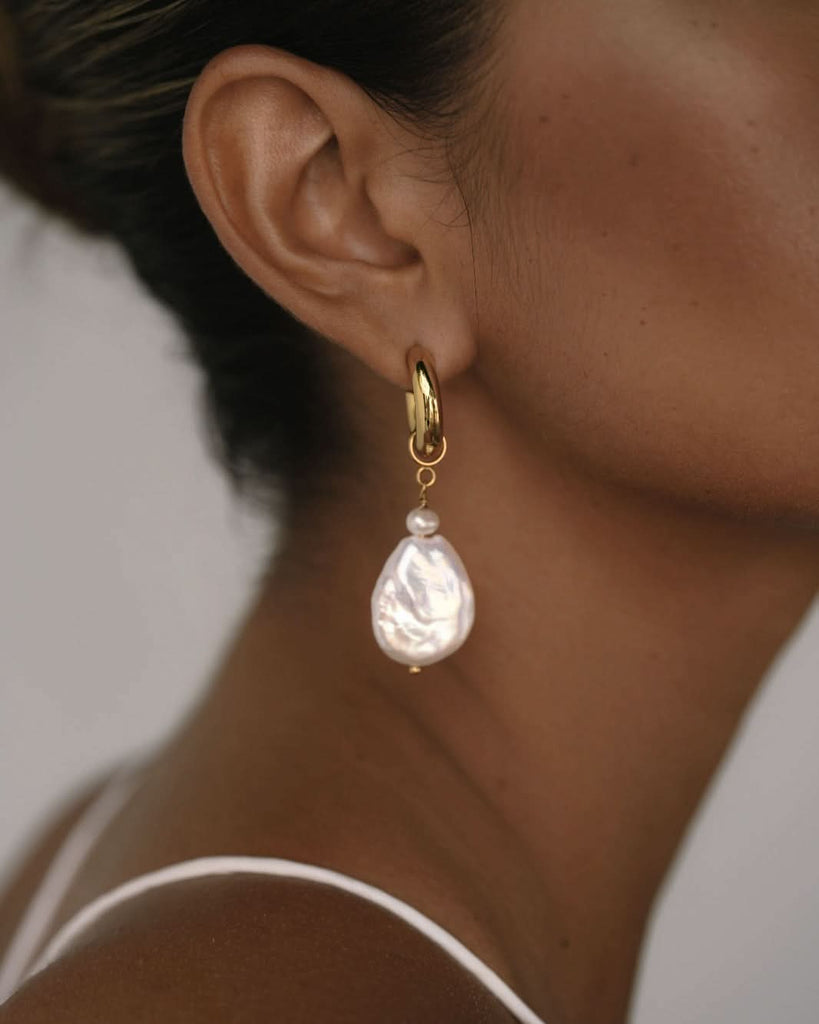 close up on baroque pearl earrings on a dark skinned model