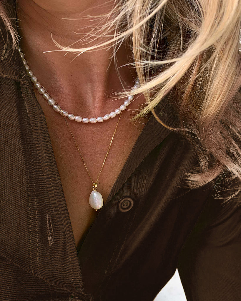 pearl pendant necklace layered with pearl choker styled with brown shirt