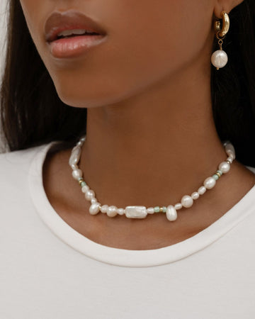 close up on a pearl choker necklace and pearl earrings