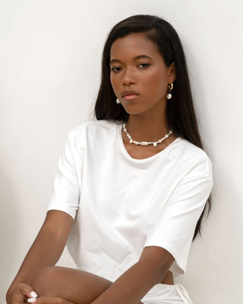 pearl choker and earrings on a model against the white wall