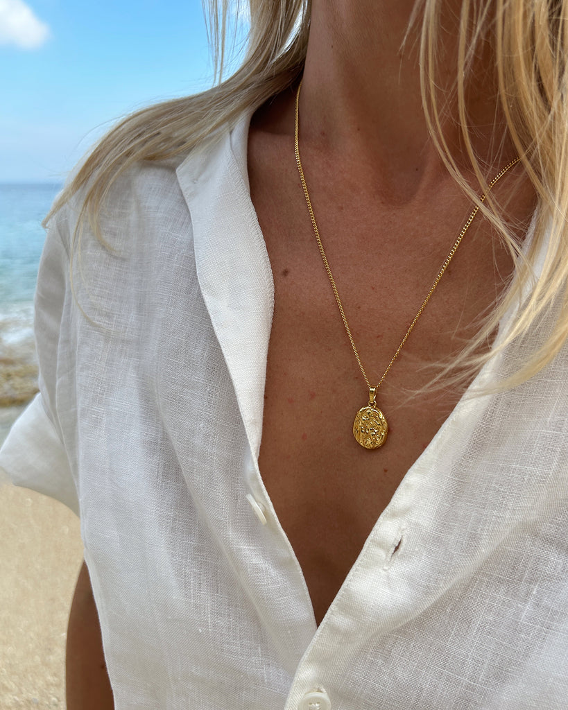 a woman wearing white shirt and gold pendant necklace