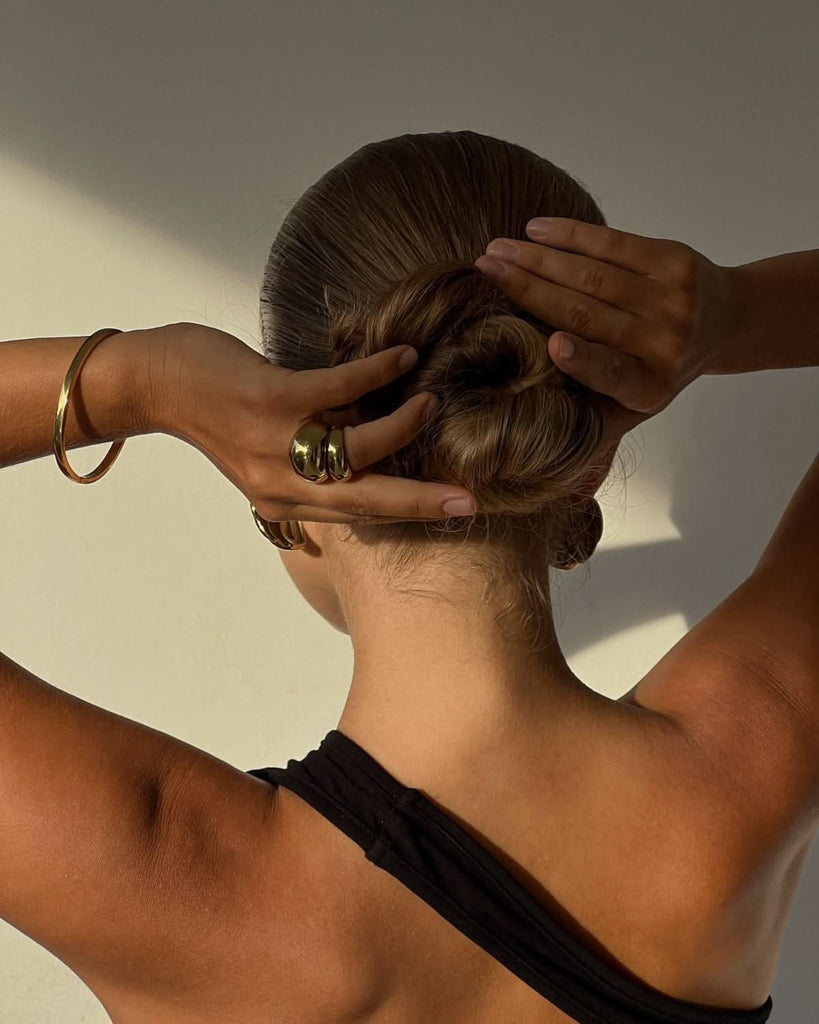 woman wearing a gold bangle and rings