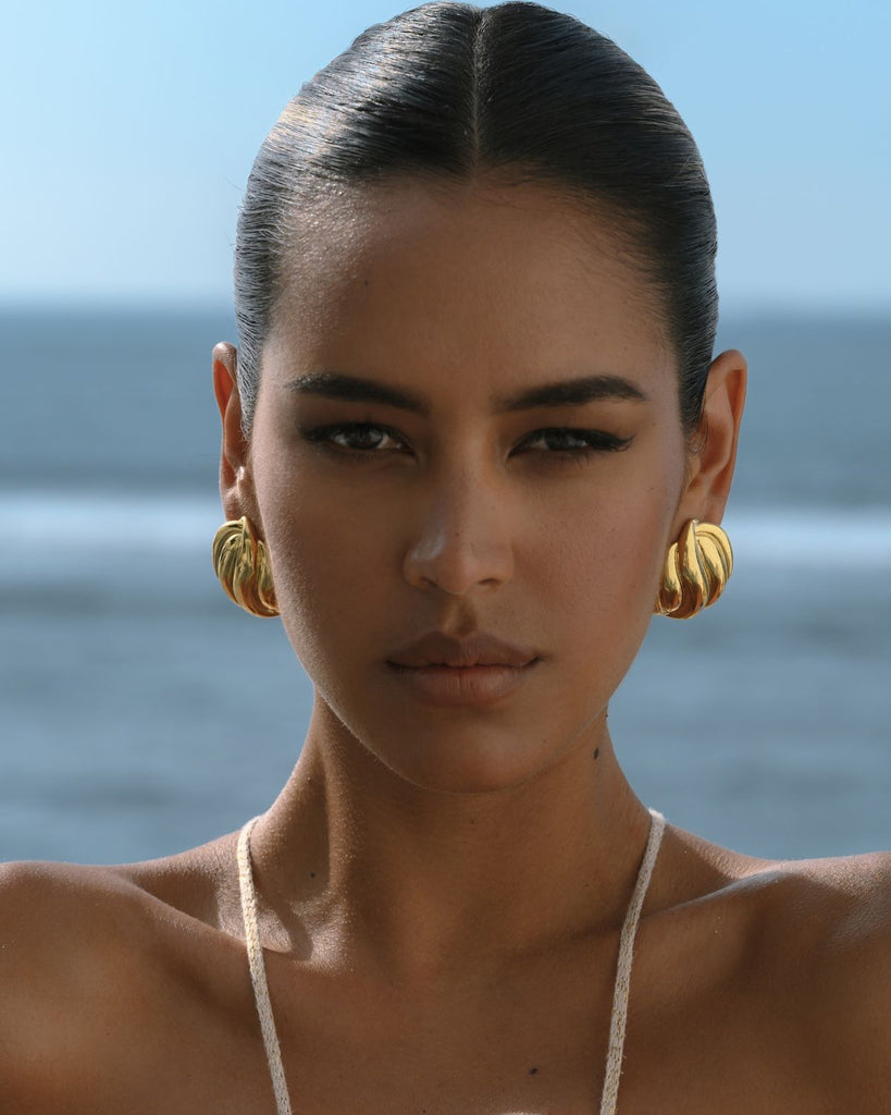 gold statement earrings on a girl with sleek hair