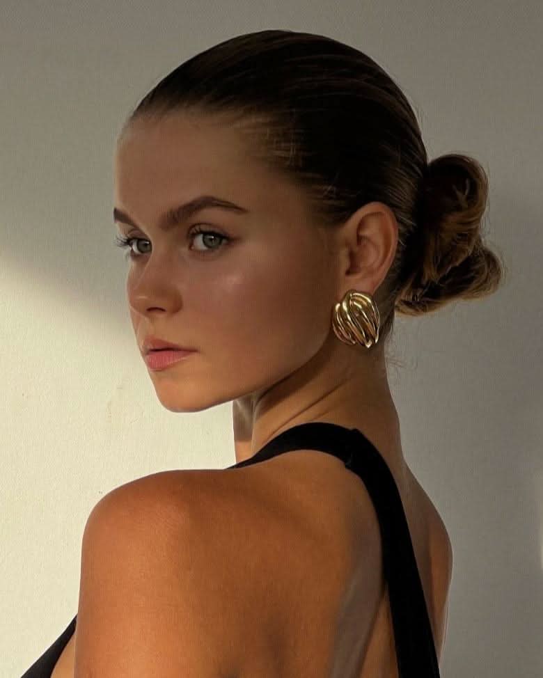 a blue eyed girl wearing statement gold earrings