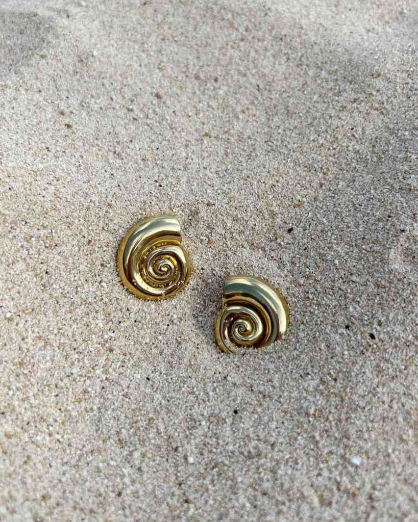 shell earrings displayed on the sand