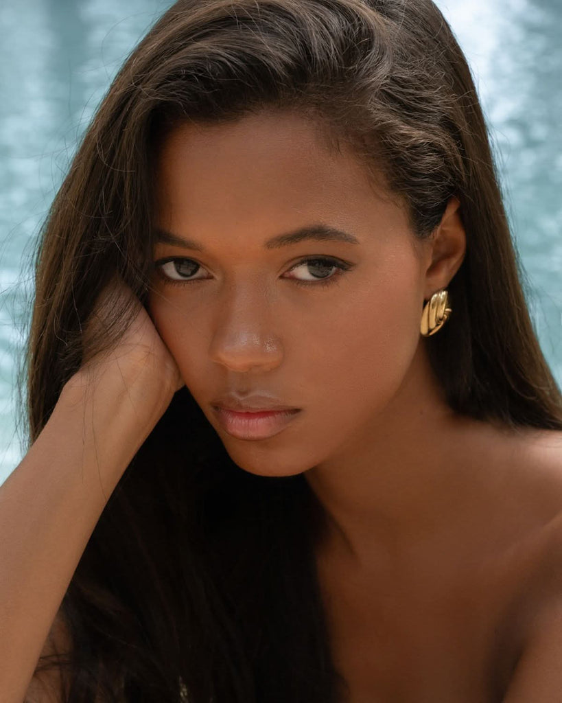 statement gold stud earrings on a girl with dark hair