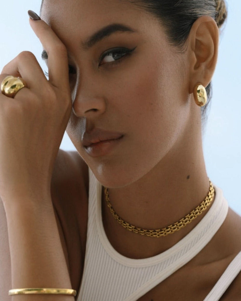 chunky gold earrings and rings set on a model
