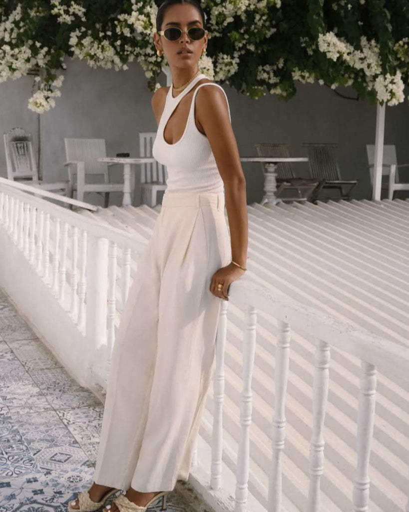 set of gold jewelry worn by a model at a white balcony