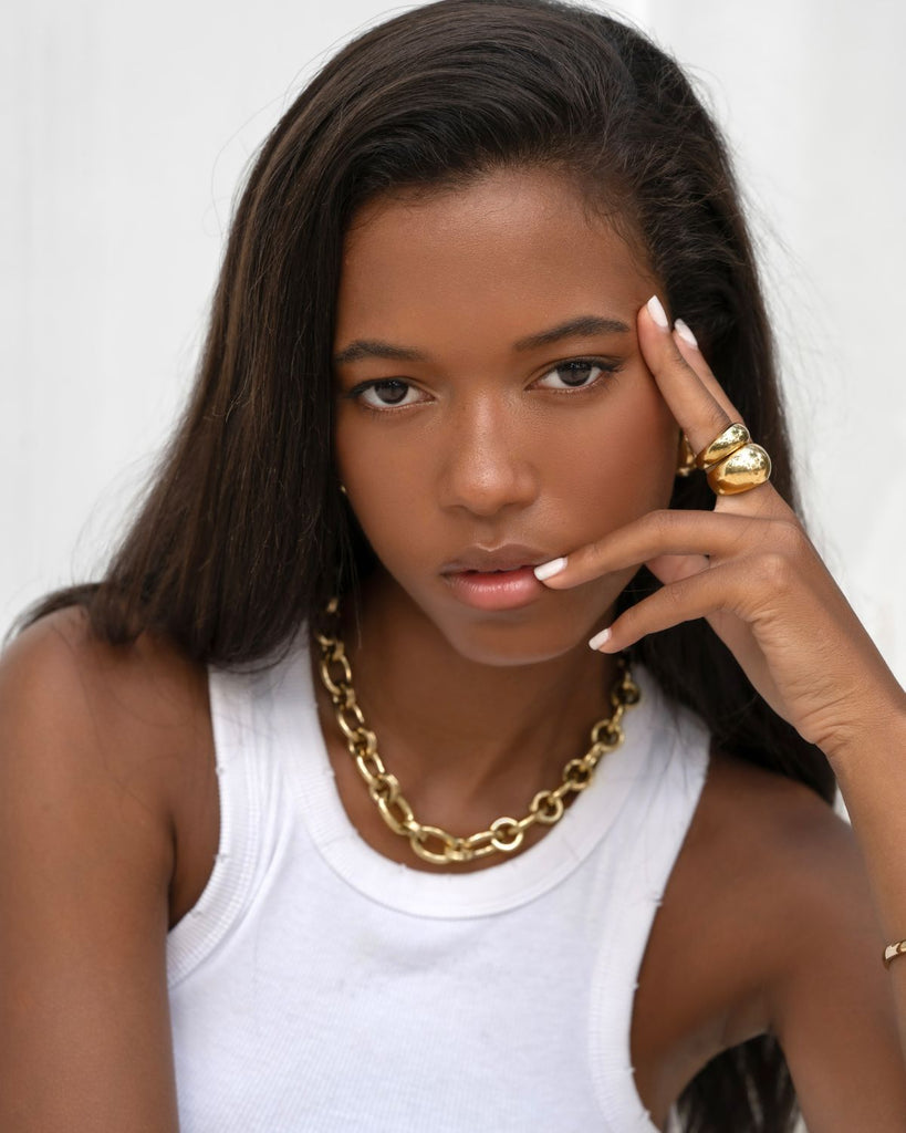 black girl wearing chunky gold necklace and rings