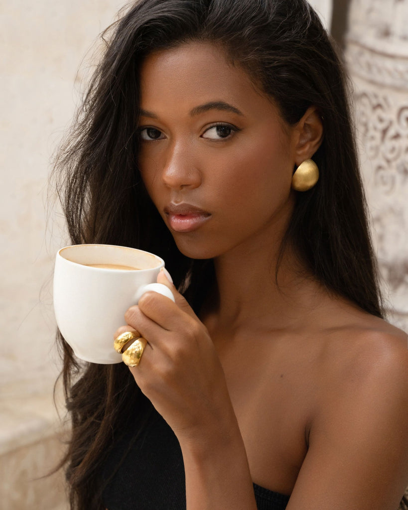 wearing gold dome earrings and rings with black top