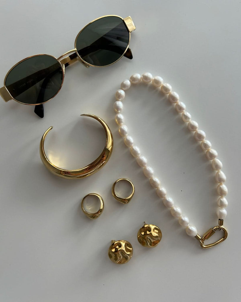 molten bangle next to pearl choker and sunglasses