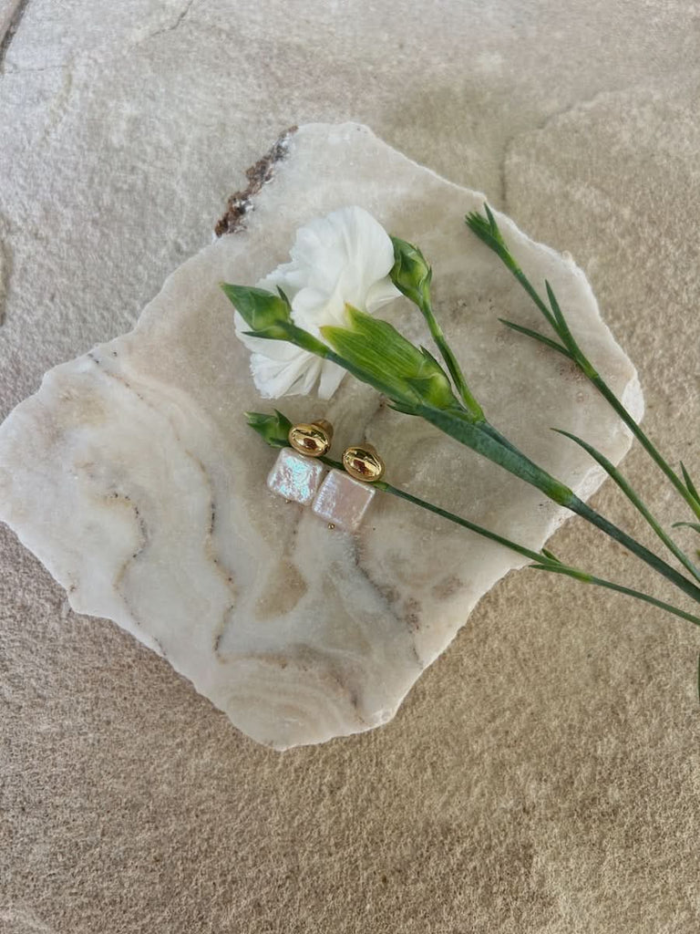 cult of sun pearl stud earrings on a stone tray