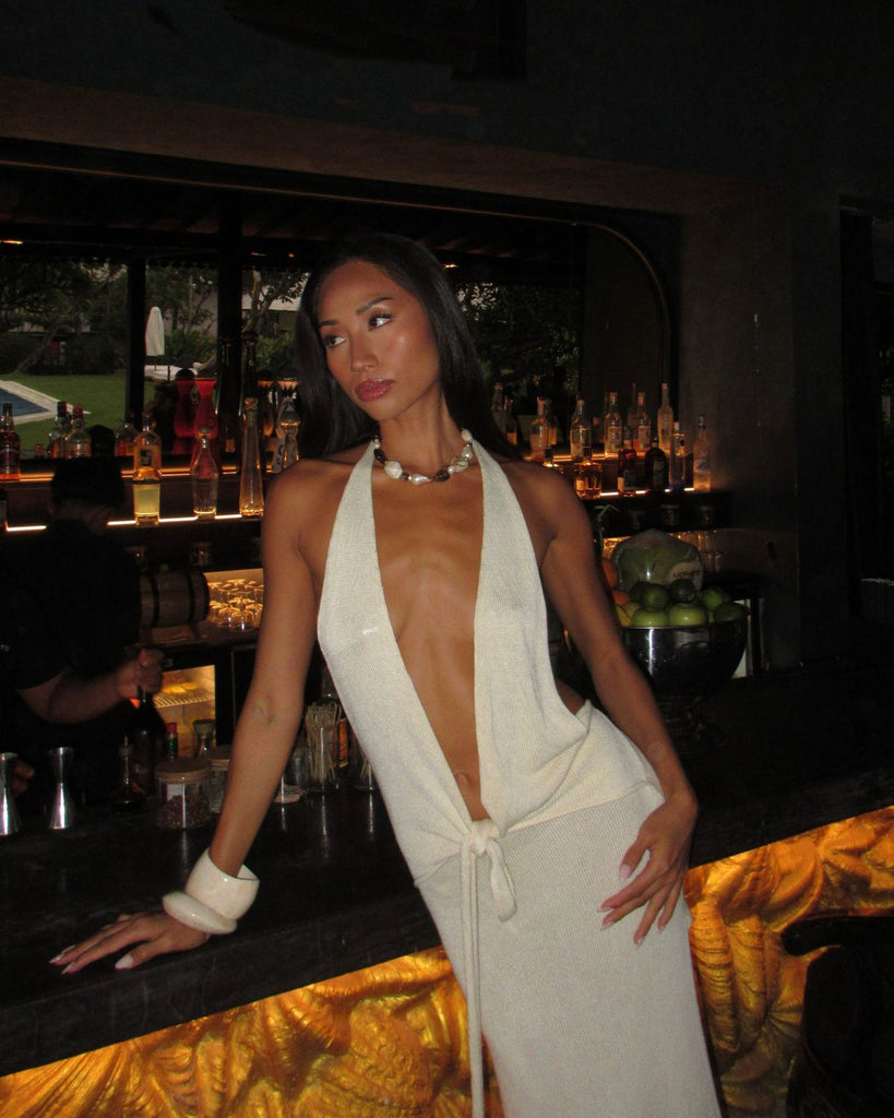 chunky beaded necklace styled with a white dress at the bar