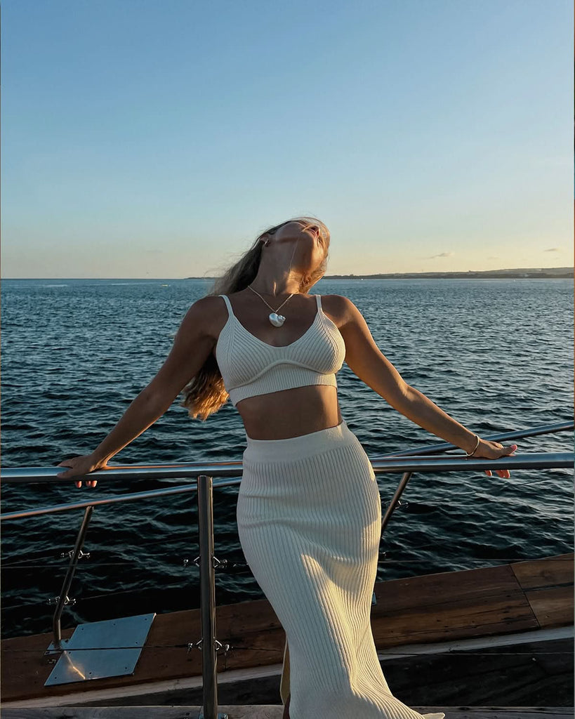 model standing posing with the bakcground of the sea wearing vacay outfit