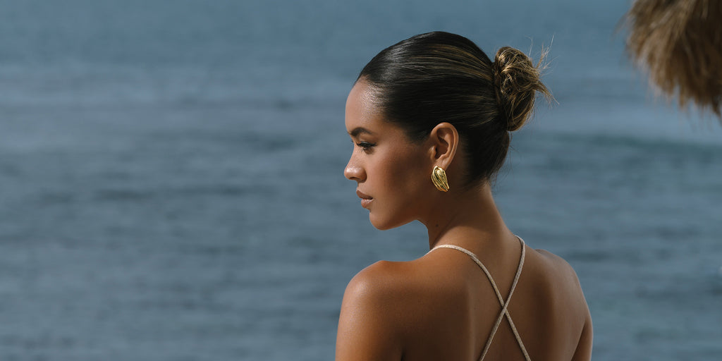 chunky gold earrings on a dark skinned model