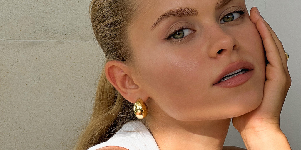 wide gold hoop earrings on a model