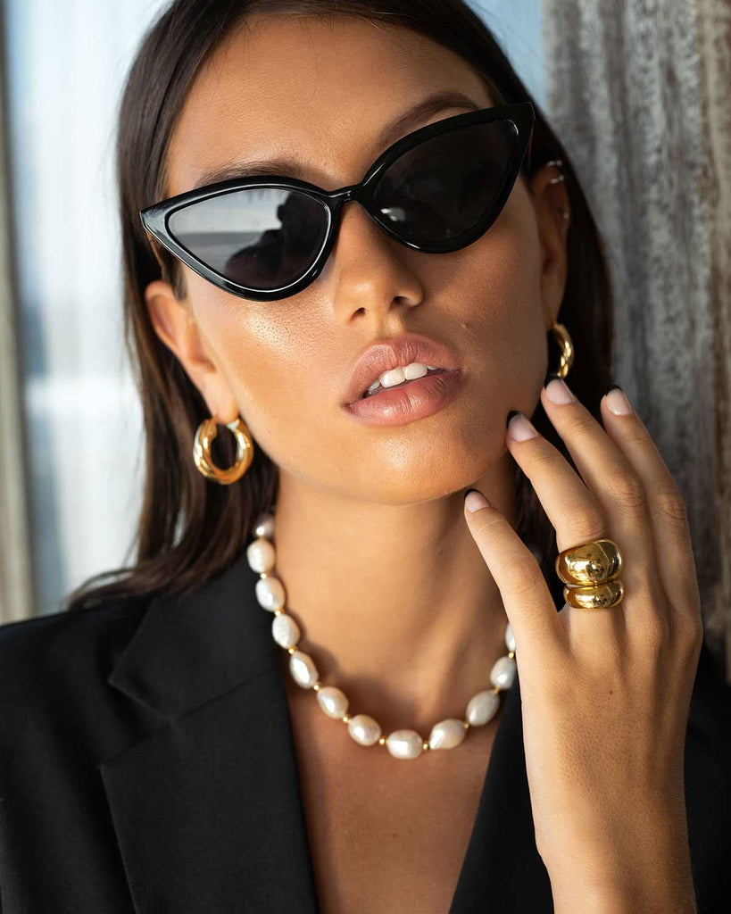 model wearing pearls, gold earrings, and rings 