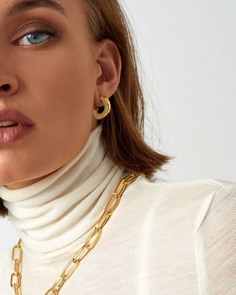 half face of model wearing gold earring and chain 