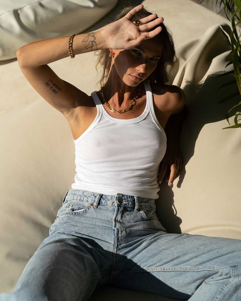 model wearing casual white tank top with jeans and jewelry 