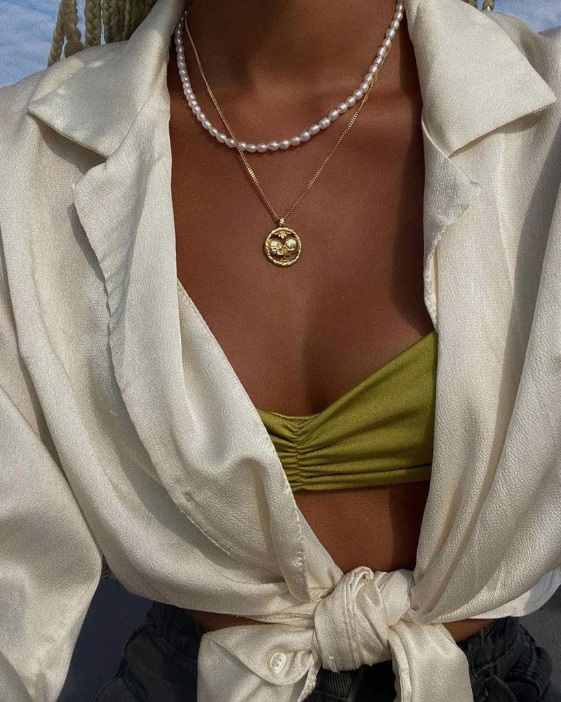 summer outfit featuring white open blouse, green bikini, a gold necklace and a pearl necklace 