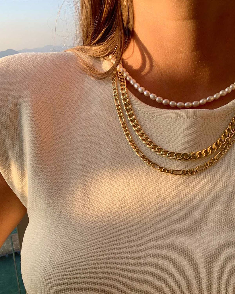 white blouse close up styled with two golden necklaces and one pearl necklace