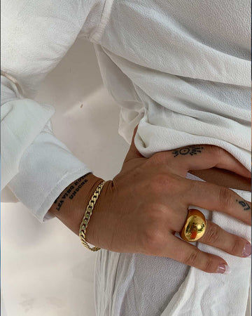 hand featuring a Cuban bracelet and large dome ring 