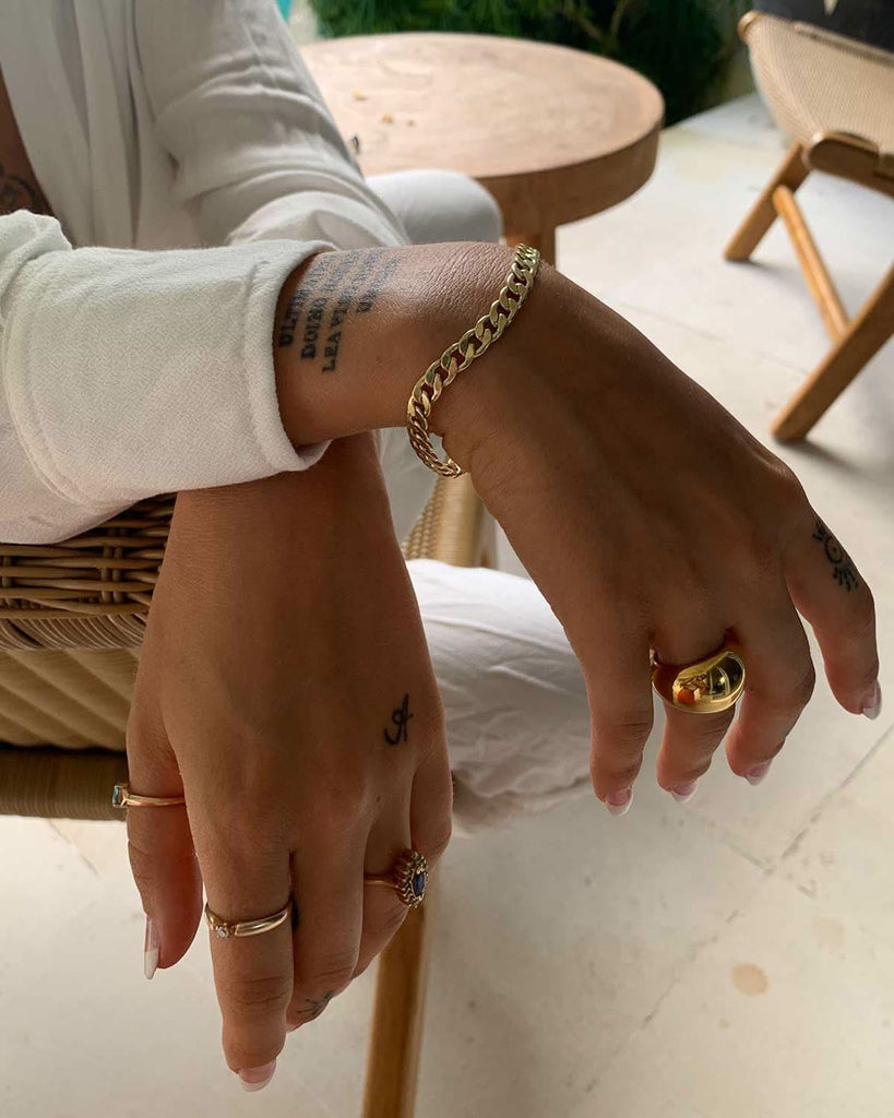 hands featuring gold rings and a Cuban chain bracelet 