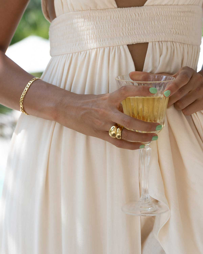 and of model holding a glass featuring two gold rings and a gold bracelet 