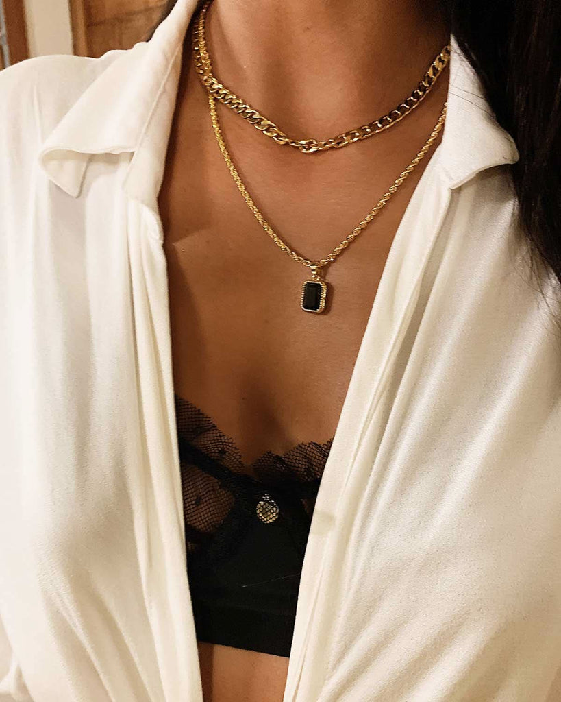 two gold and black chain necklaces styled with black lingerie 