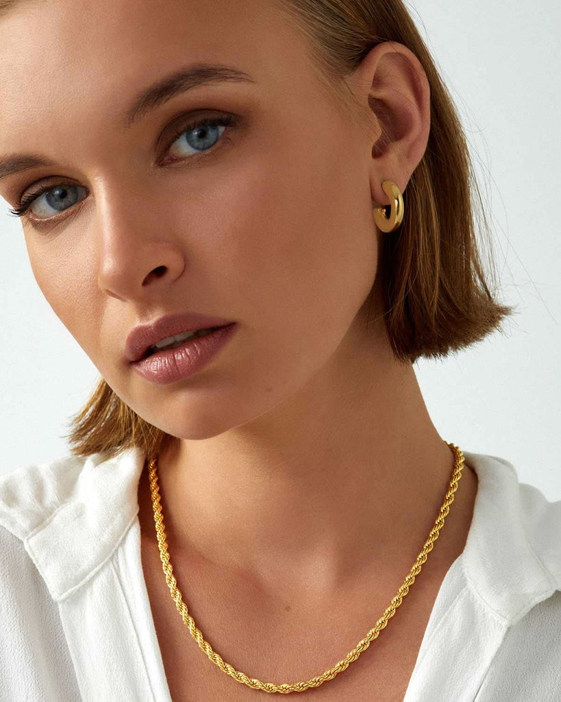 model close up wearing twisted chain necklace and small hoop earring 