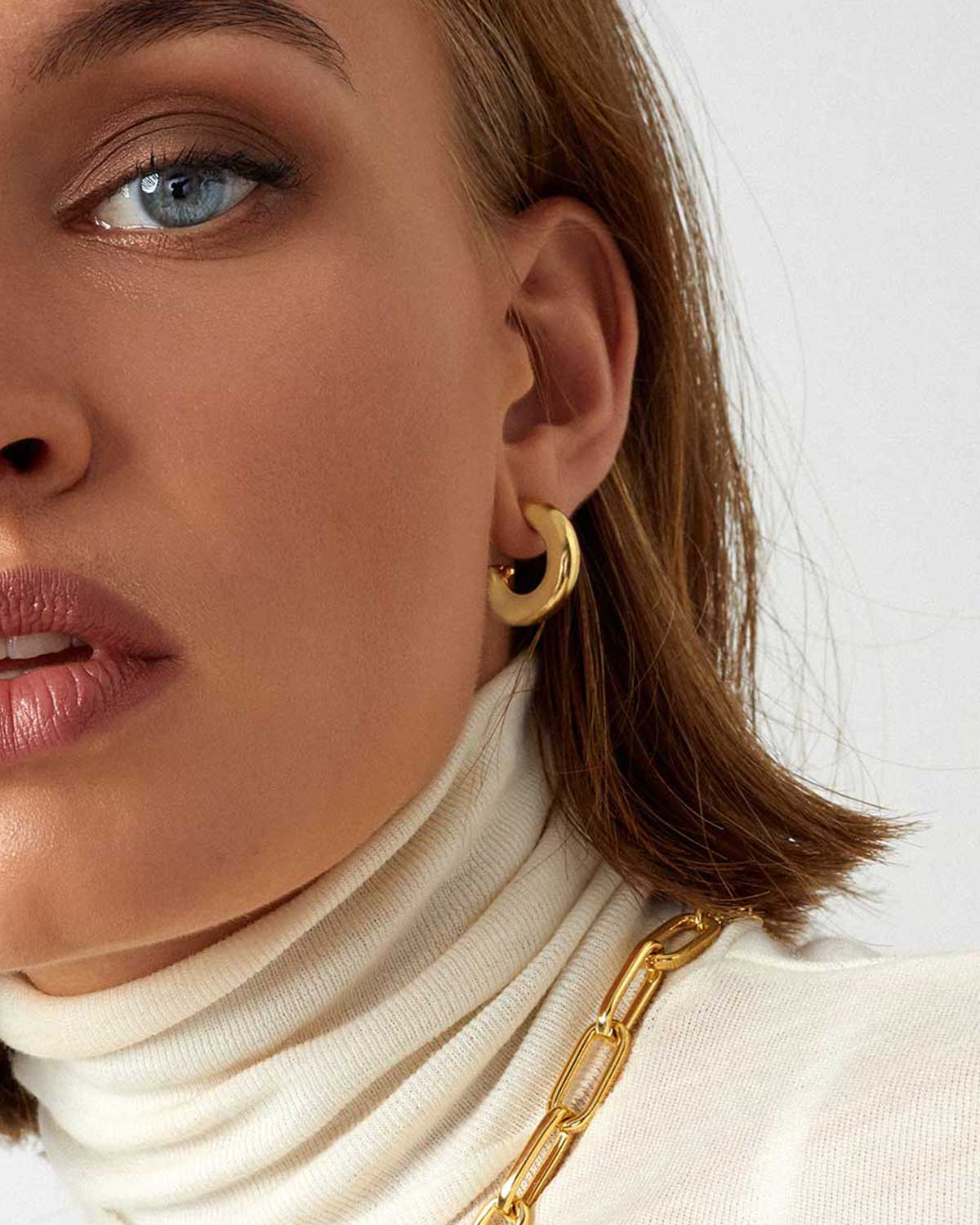 half face close up wearing gold hoop earring and necklace 