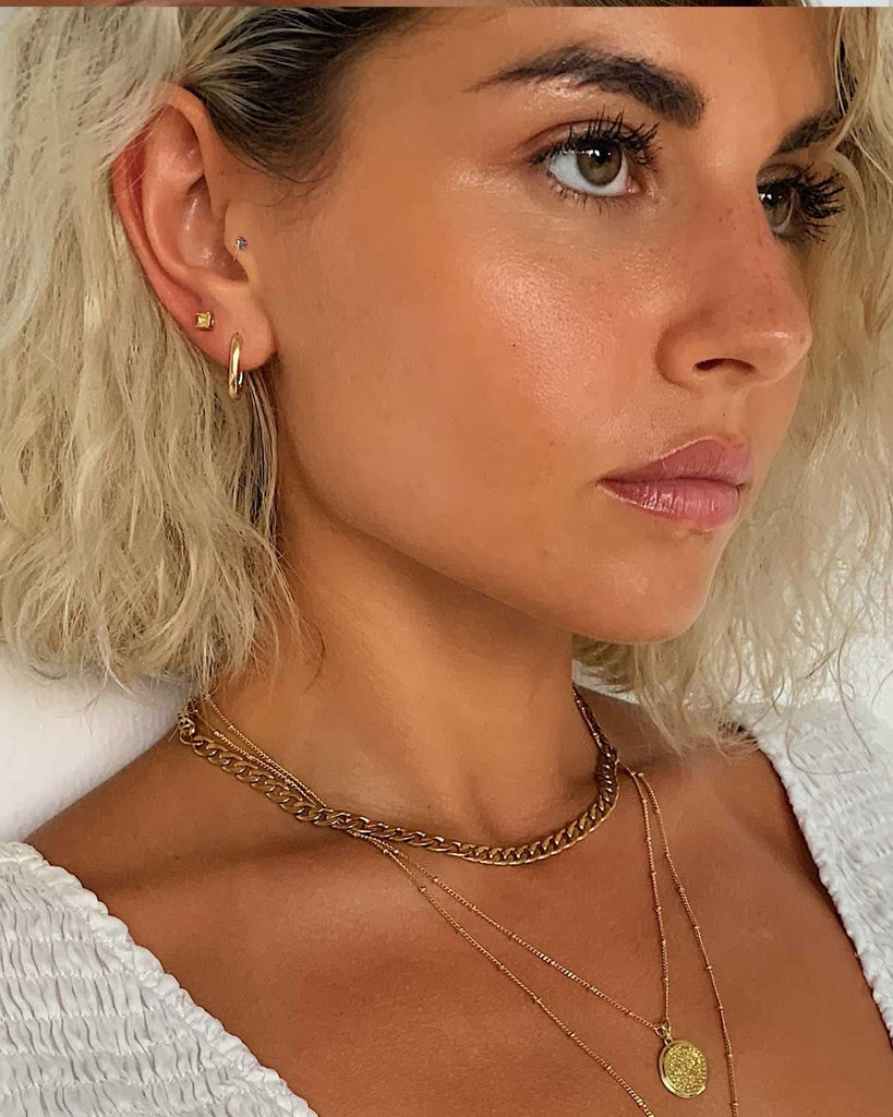 Model face and neck featuring gold jewelry 