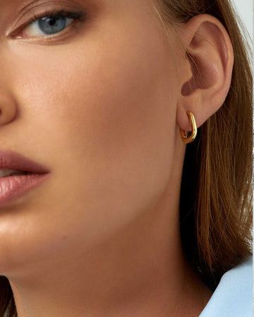 face close up wearing a single small gold rectangle hoop 