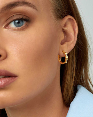 half face of model wearing gold and crystal earring 