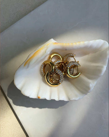 Sets of pave hoop earrings on a shell 