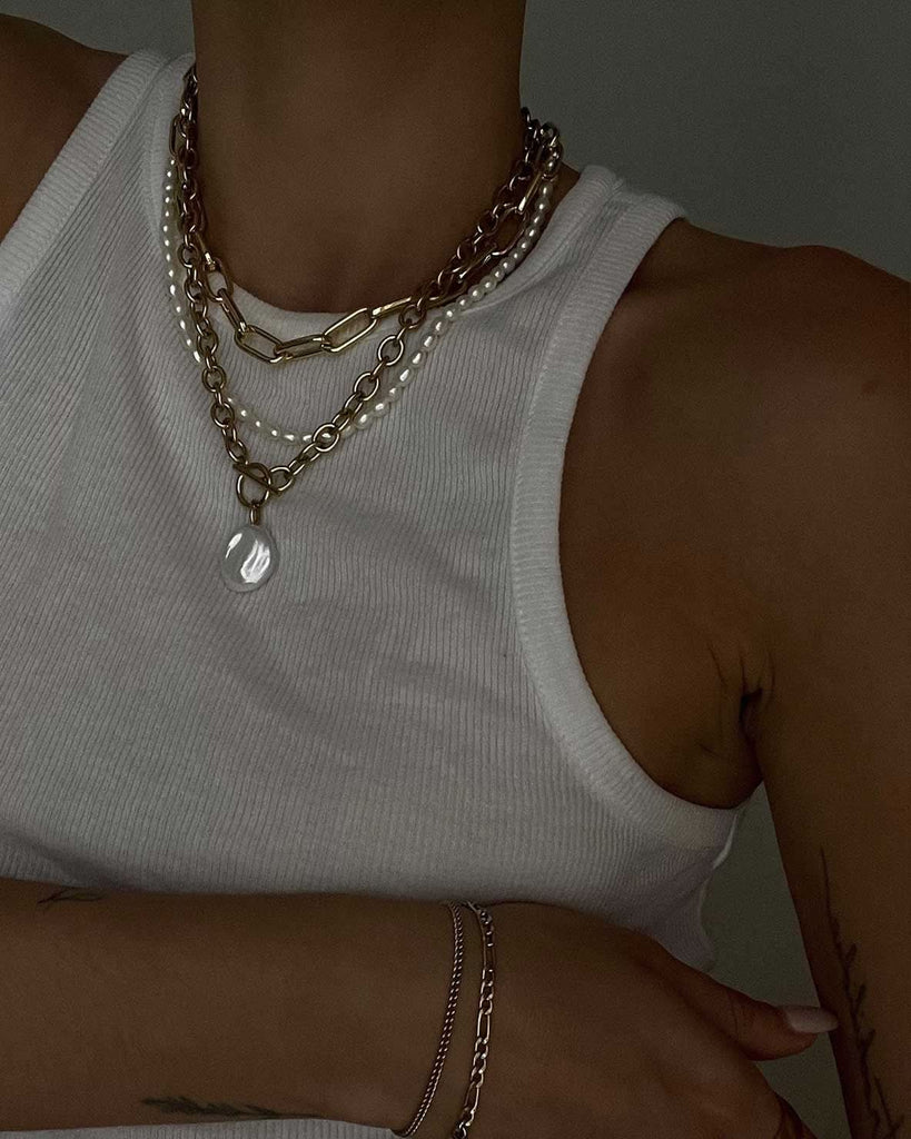 white tank top styled with a gold and pearl necklace