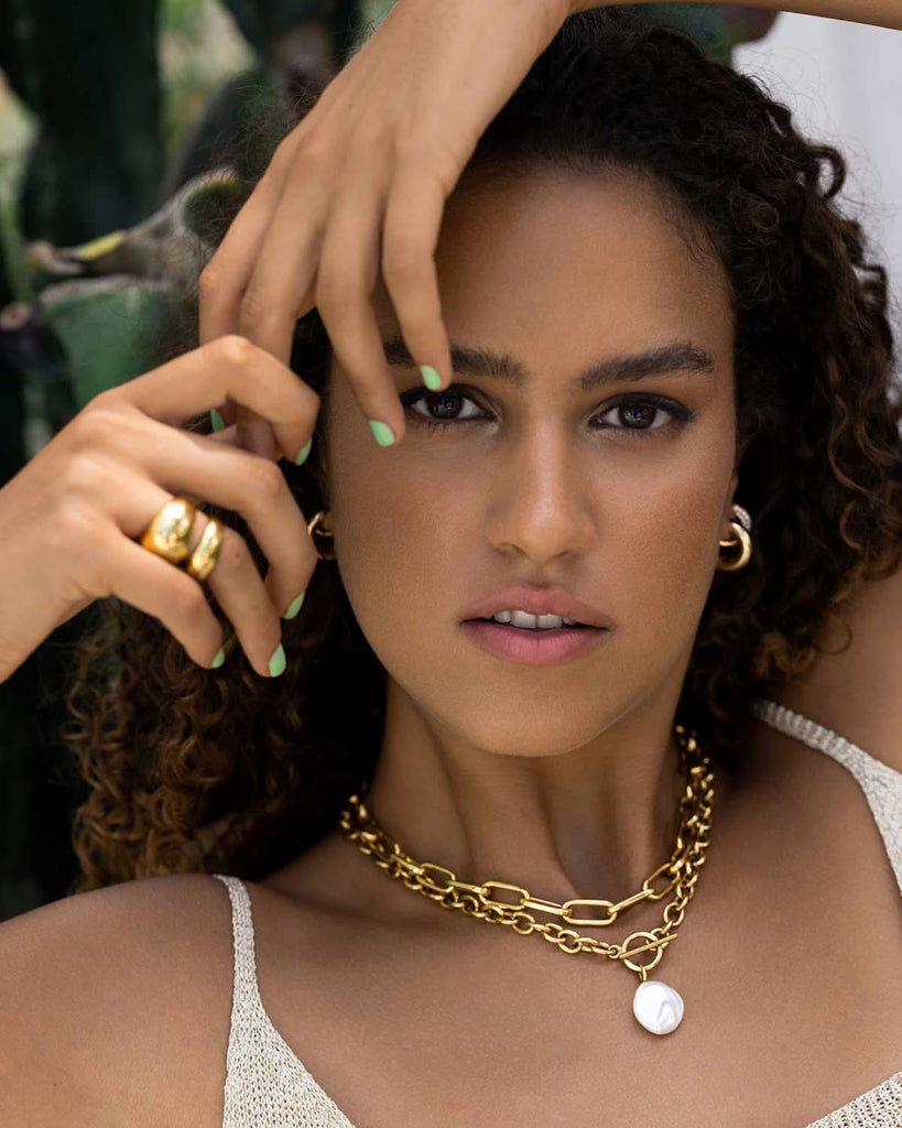 curly model wearing chunky pearl layered necklaces