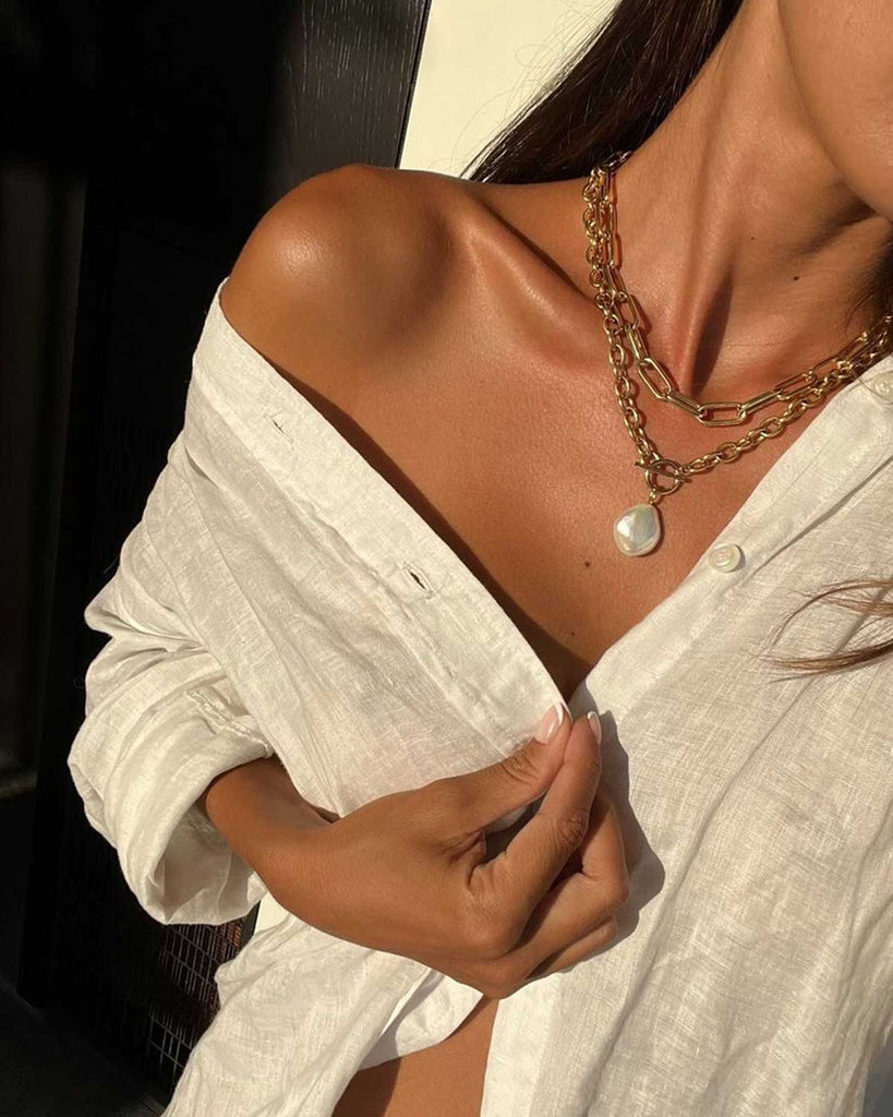 neck and sholder of model wearing a white linen shirt and golden jewelry
