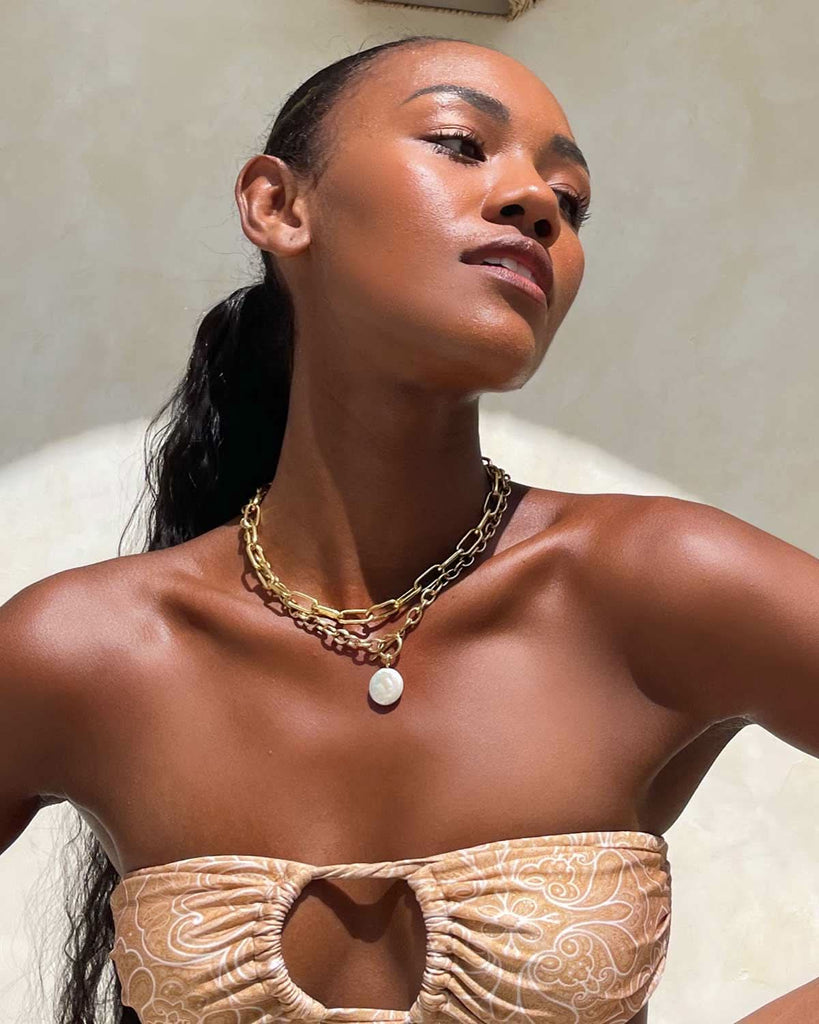 naked neck and shoulders wearing two gold necklaces 