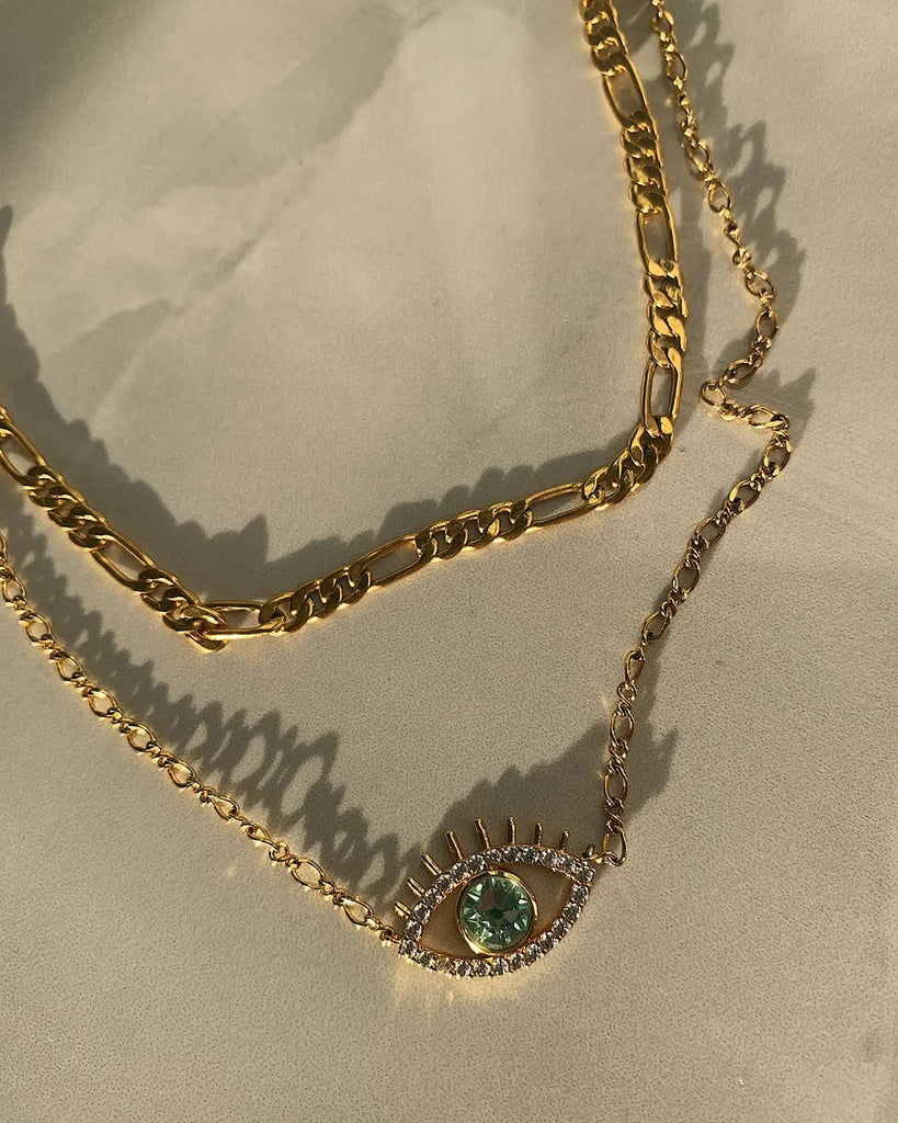 chunky gold chain necklace with evil eye chain necklace on sandy tile