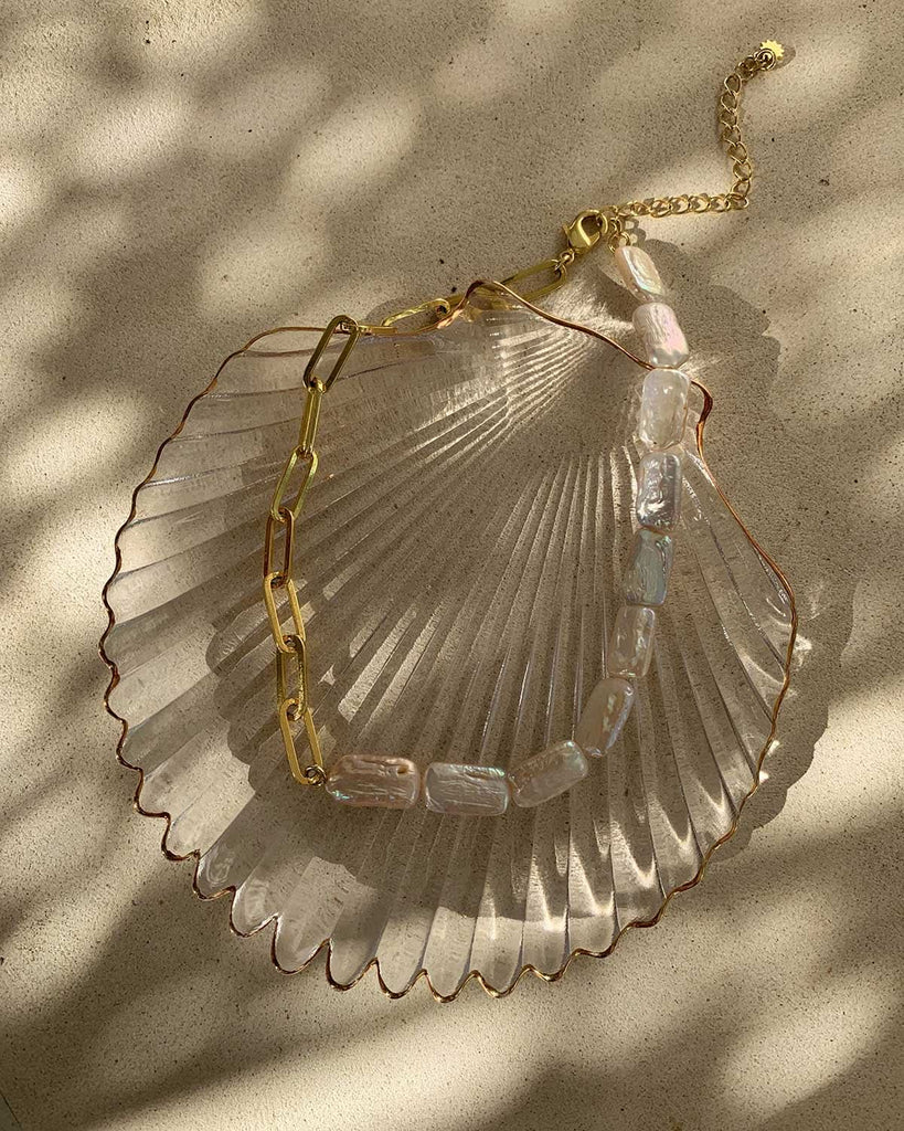 half pearl choker on a glass shell plate 