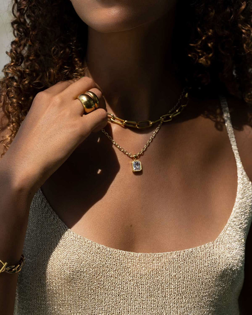 crystal and gold pendant necklace styled with gold bracelet and rings 